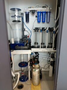 Image shows an aquarium filtration system with pipes, filters, cylinders, and a CO2 tank installed in a small utility room.